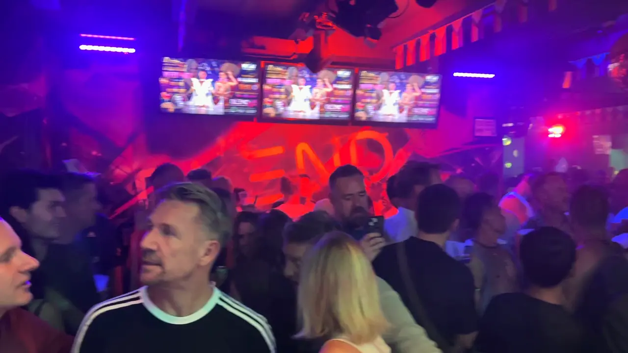 Een volle avond in Blend XL: de menigte onder de schermen, de BLEND-muur in rood licht en de ingang naar de straat.